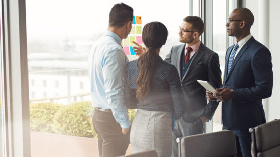 Diverse,Multiracial,Management,Team,Standing,Grouped,In,Front,Of,A